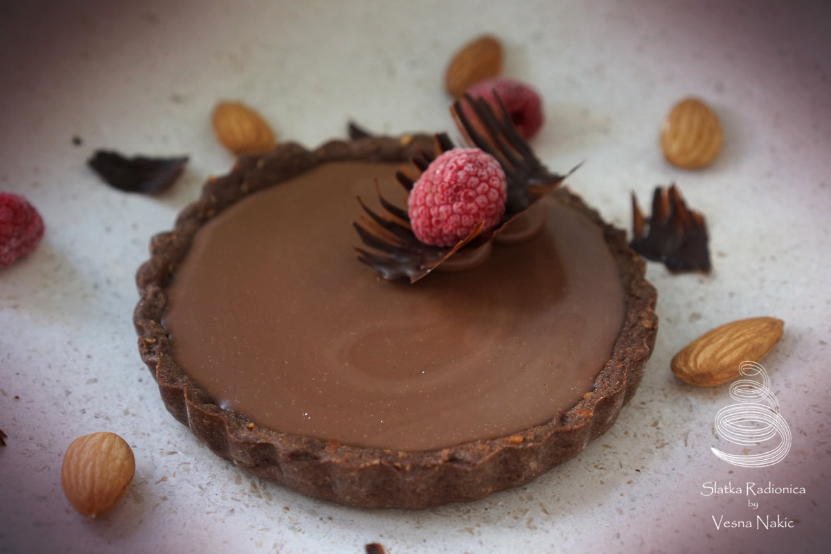 čoko tart monoprcija, dekorirana ukrasnom od čokolade i malinom