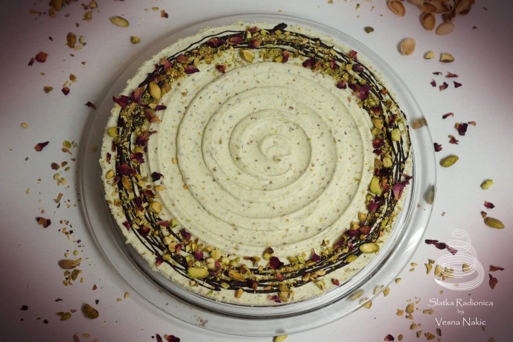 Torta od pistacija i čokolade, ukrašena tamnom čokoladom, komadićima pistacija i laticama suhih ruža