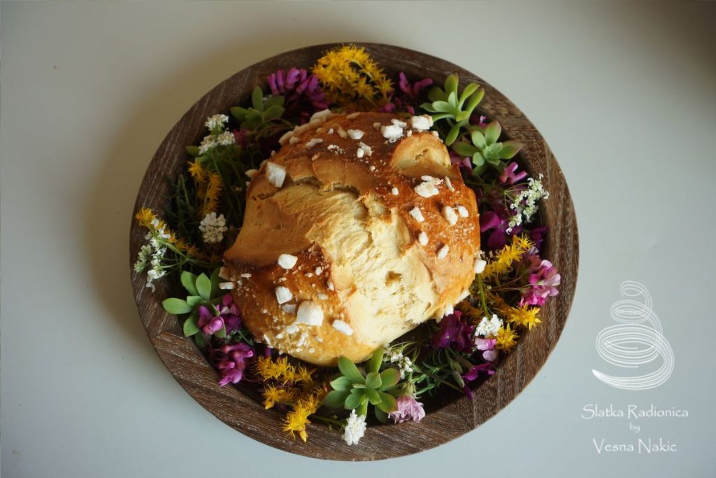 Pinca, pogača ili sirnica na drvenom poslužavniku ukrašena poljskim cvijećem