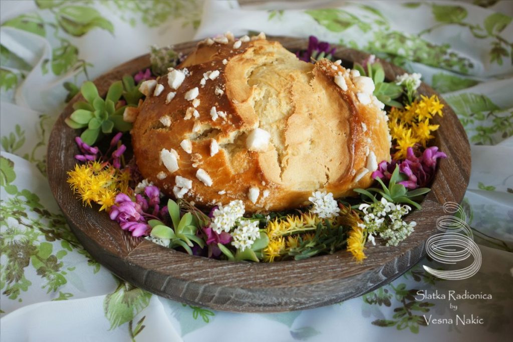 Pinca, pogača ili sirnica na drvenom poslužavniku ukrašena poljskim cvijećem