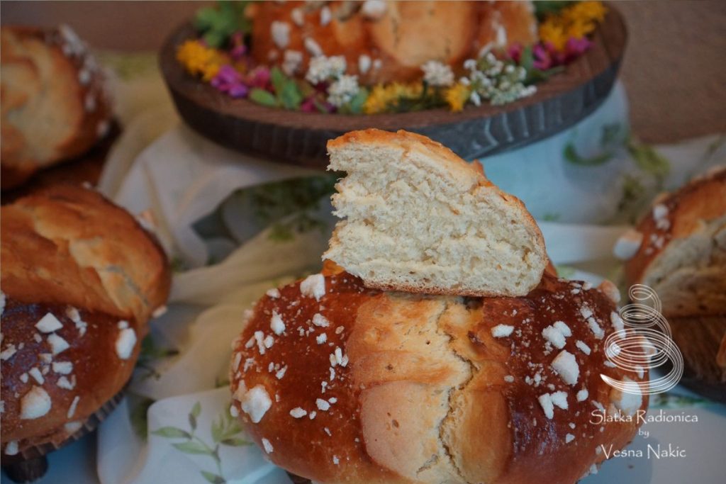 Pinca, pogača ili sirnica, izrezan komad da se vidi presjek, na drvenom poslužavniku ukrašena poljskim cvijećem