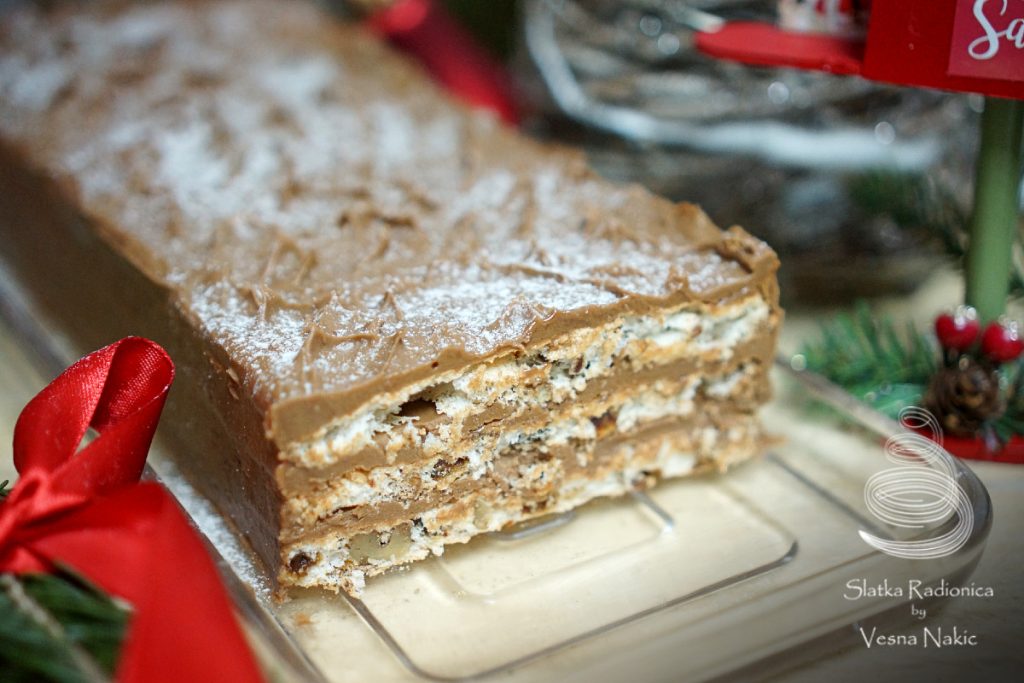 Mamina torta s datuljama - presjek torte servirane na staklenom pladnju, na drvenoj podlozi s blagdanskim detaljima u zeleno-crvenim bojama